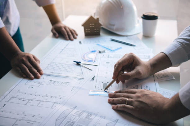 istock Architect working on blueprint discussing new project with colleague in office. 1326009275