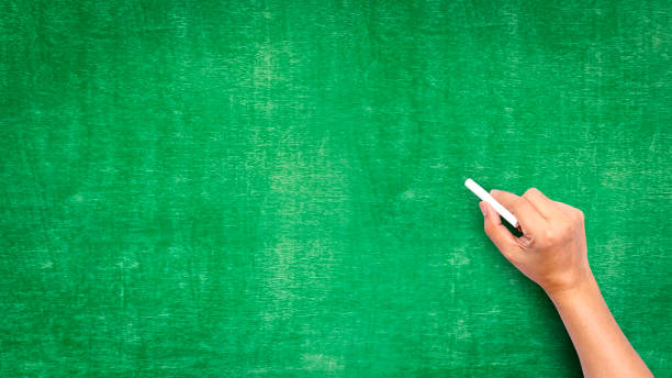 istock hand holding chalk writing on green chalk board good texture idea for text or background for copy space. 1326010124
