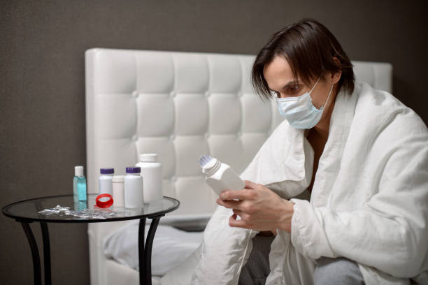 istock A handsome young man is ill and takes medication while staying at home to prevent spreading of coronavirus. 1326010161