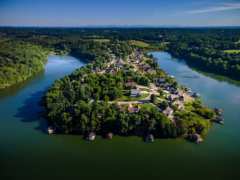 Neighborhood of homes on a peninsula surrounded by the Tellico Reservoir Lake with trees and clear sky