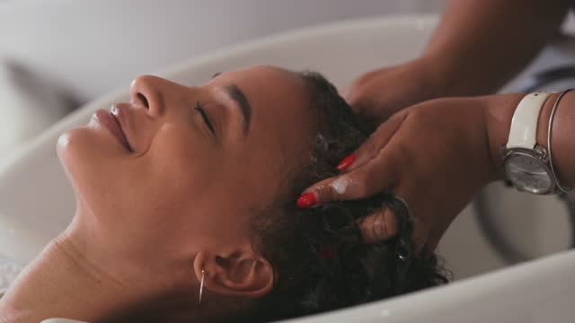4k video footage of an attractive young woman getting her hair washed at a salon