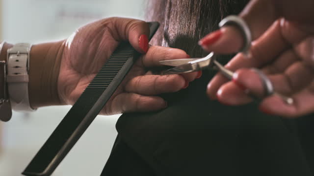 4k video footage of an unrecognizable woman sitting and getting a haircut by a hairdresser in a salon