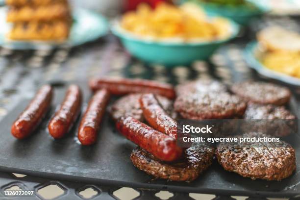 Beef Burgers And Bratwurst Bangers Outdoor Bbq Grilled Western Colorado Cooking Photo Series Stock Photo - Download Image Now