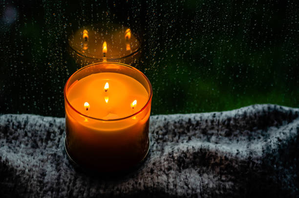 istock Burning aroma candle puts on table near by window that have rain drop 1326022589