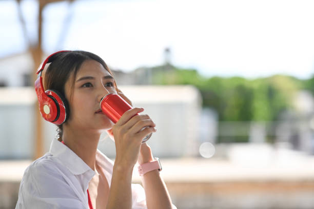 istock Young woman in headphone drinking soda refreshment from a can. 1326022681