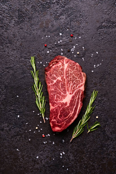 istock Fresh raw marbled beef rib eye steak and spices on black stone background 1326022805