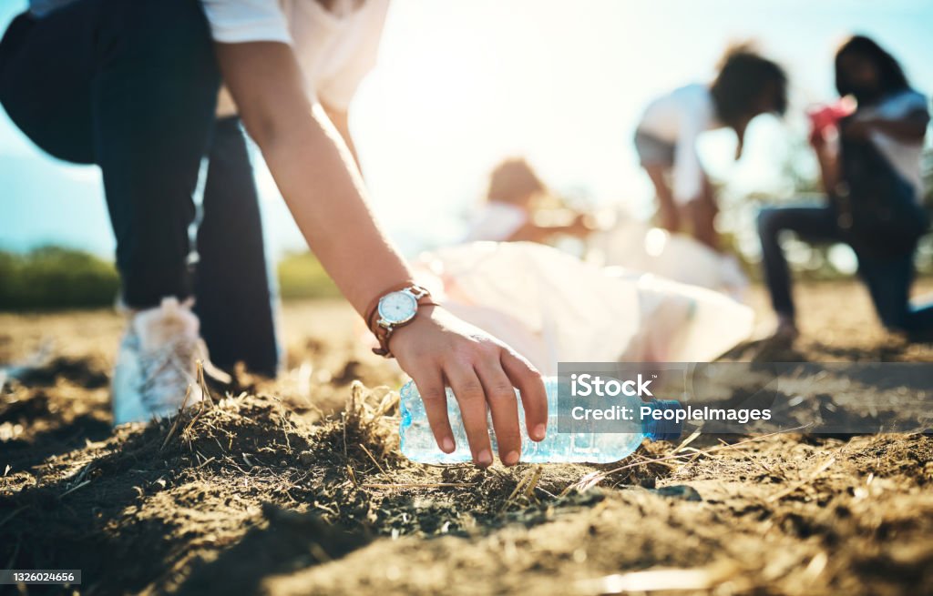 Shot of an unrecognisable teenager picking up litter off a field at summer camp If it's not made by nature, it doesn't belong in nature Recycling Stock Photo
