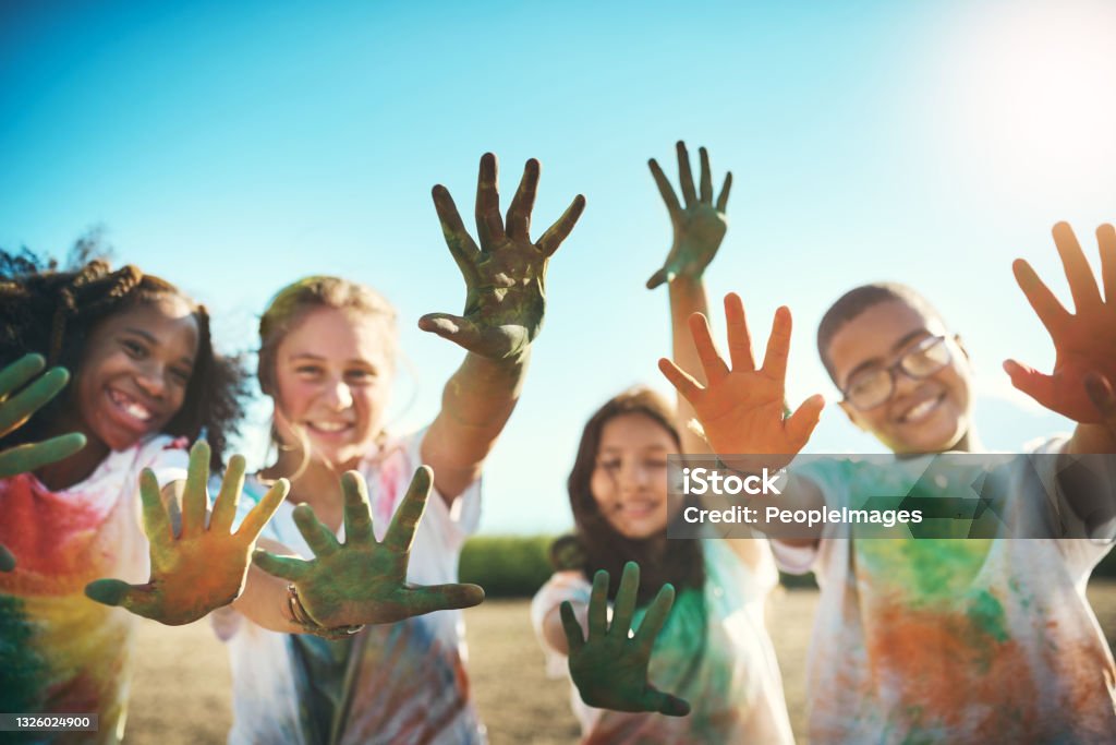 Shot of a group of teenagers having fun with colourful powder at summer camp Getting our hands dirty and having a great time Child Stock Photo