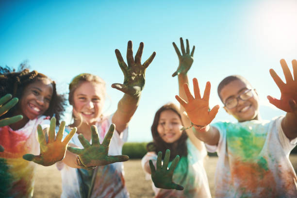 shot of a group of teenagers having fun with colourful powder at summer camp - photography friendship vacations horizontal imagens e fotografias de stock