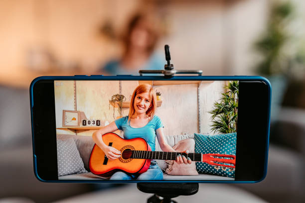 istock Woman making tutorial of playing guitar on phone 1326025836