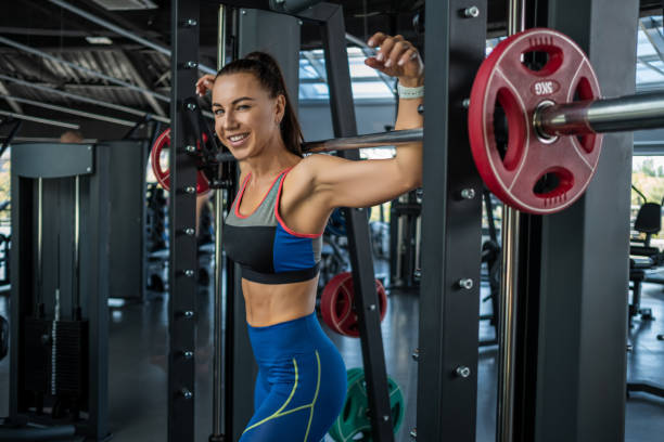 istock Cheerful fit young brunette standing near Smith machine at gym 1326026149