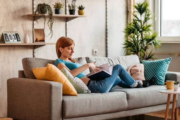 istock Woman At Home Lying on sofa and reading book 1326026952