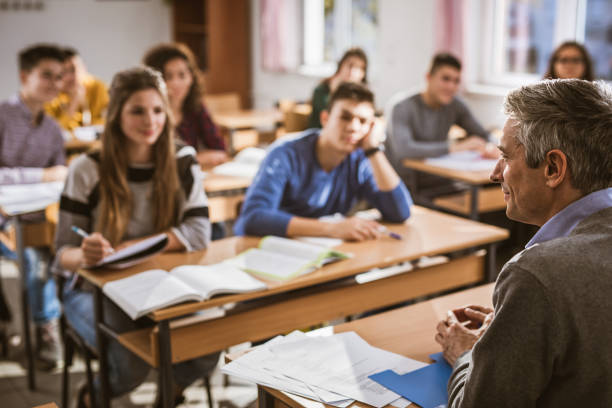 istock Profile view of a professor teaching a lecture at high school. 1326030829