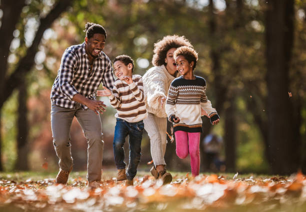 istock Happy black parents having fun while chasing their small kids in autumn day. 1326031136