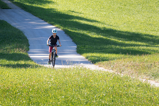 Girl child riding mountain bike into the sunset. Beautiful golden summer light.