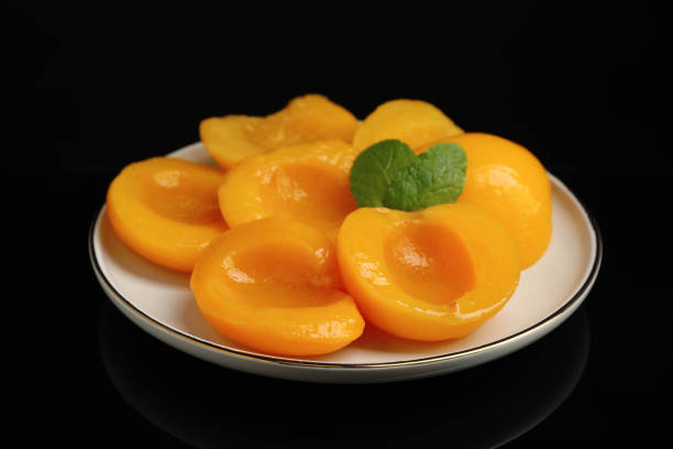 istock Plate with canned peach halves on black background 1326032266