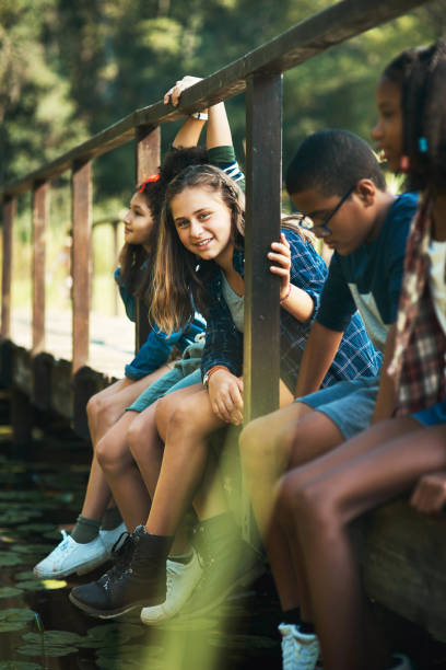 plan d’un groupe d’adolescents assis sur un pont dans la nature au camp d’été - teenager team carefree relaxation photos et images de collection