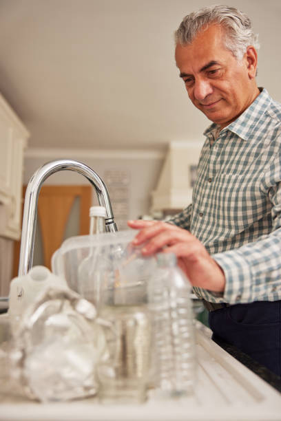 istock Mature Man At Home In Kitchen Washing Used Packaging  Before Recycling 1326036629