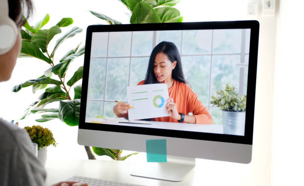istock Video conference, Work from home, Asian woman holding business chart while making video call to business team with virtual web, Contacting colleague by conference on computer at home 1326037820