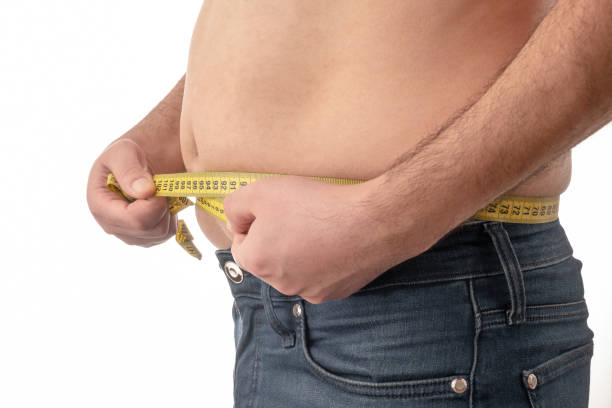 big belly man measuring his waist with tape measure - belly button imagens e fotografias de stock