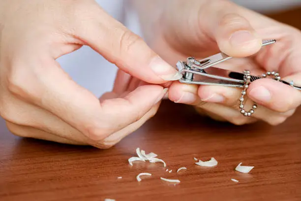 Close-up woman's fingernails are being trimmed with nail clippers. The concept of care, clean fingernails.