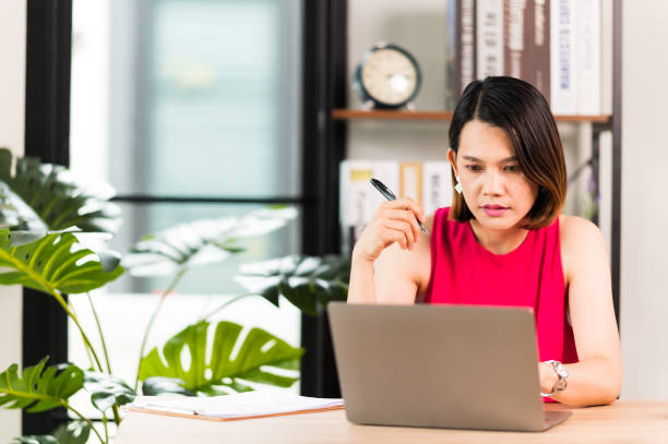 istock A middle-aged Asian woman work at home office check information online using laptop 1326041670