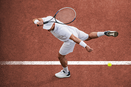Sport. Top view of male tennis player hitting ball with racket.