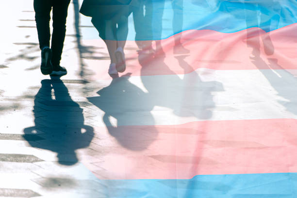 transgender flag, shadows and silhouettes of people on a road, conceptual picture about anonymous transgender and gay lesbian in the world - transgender stockfoto's en -beelden