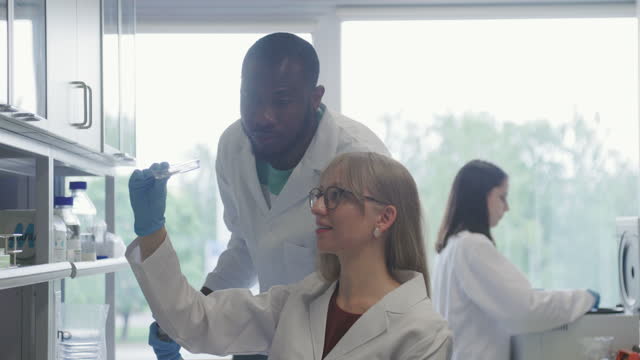 Male and female biotech scientist examining cultured meat in petri dish