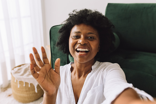 African woman waving hand on video call. Mature female making a video call.