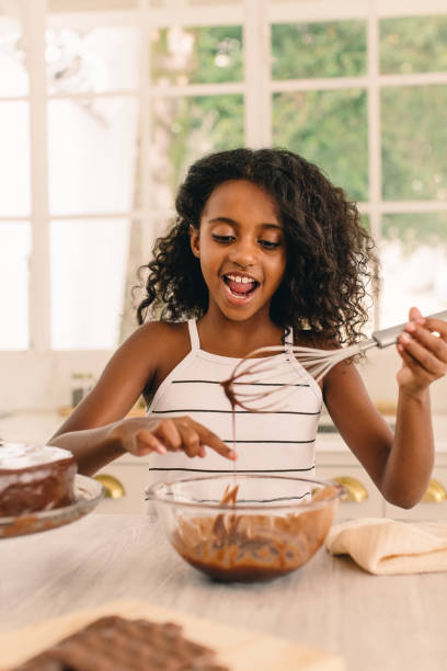 istock Small girl licking chocolate cream in kitchen 1326047663