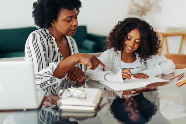 mère aidant sa fille dans ses devoirs - home schooling photos et images de collection