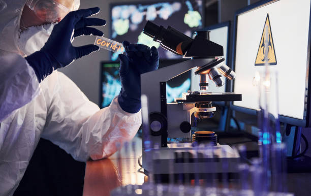 istock Side view of scientist in white protective uniform that works with coronavirus in laboratory 1326048512