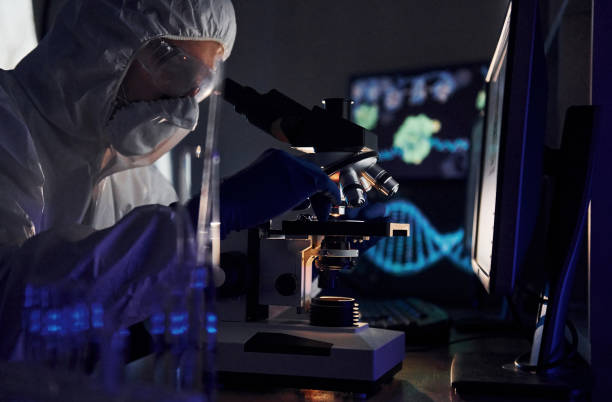 istock Side view of scientist in white protective uniform that works with coronavirus in laboratory 1326048967