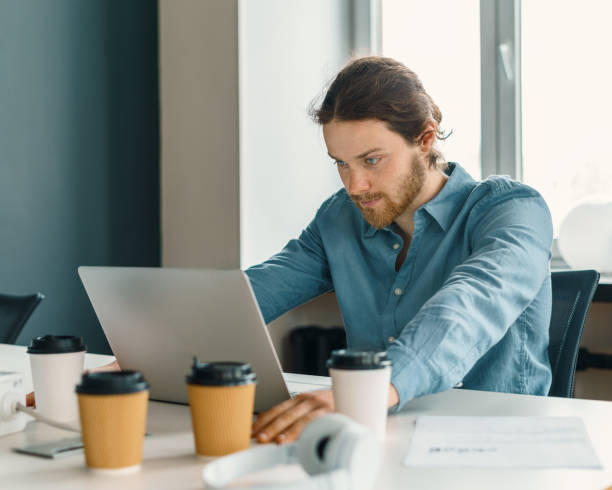 istock Stressed young male office worker trying to concentrate while working on laptop 1326049067