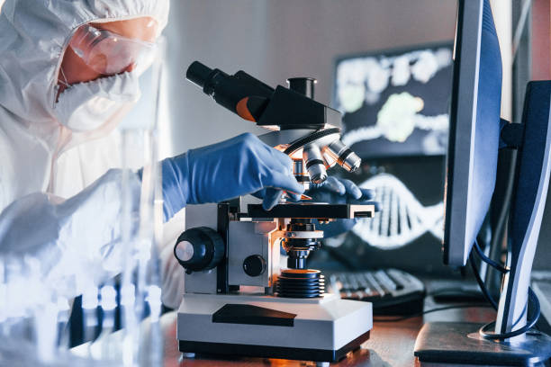 istock Side view of scientist in white protective uniform that works with coronavirus in laboratory 1326049090