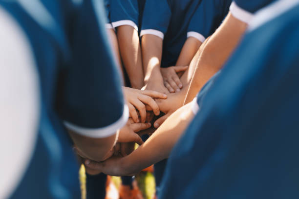 equipe de esportes ssports equipe empilhando mãos juntos em um grupo. companheiros de equipe felizes motivados em uma equipe. atividades de construção de equipes e aumento da moral dos jogadores esportivos. estudantes construindo espírito de equipe ant - equipa internacional de futebol - fotografias e filmes do acervo