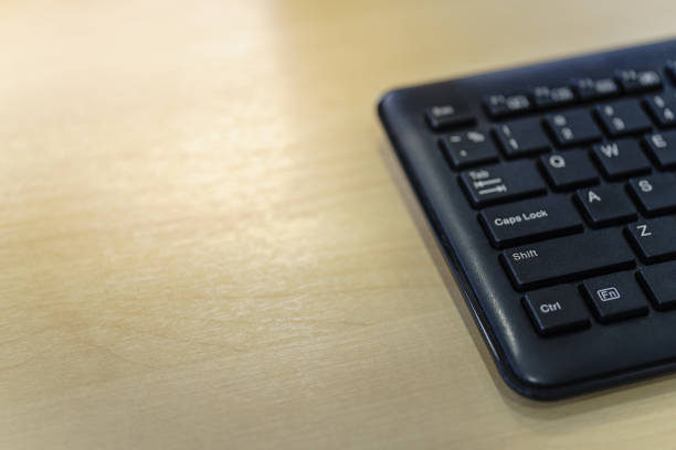 Closeup of black computer keyboard on wooden table with copy space.