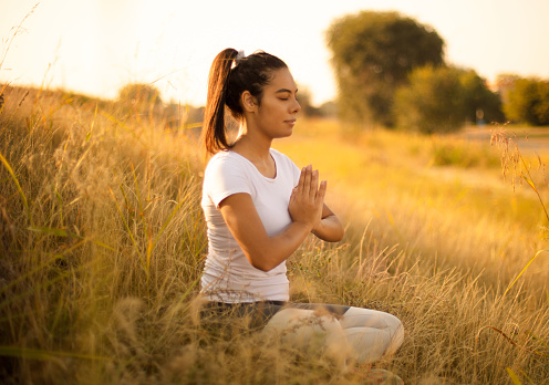 African young woman in nature sitting in yoga position.