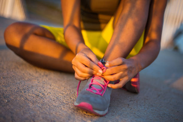 Unrecognizable Fit African Sportswoman Tying Shoelaces on Sneakers. Close up.