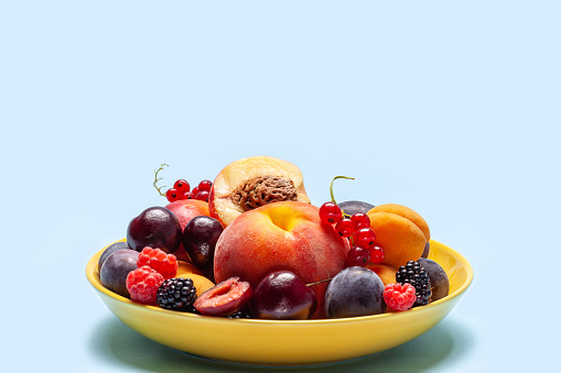 Peaches, apricots, raspberries, cherries, currants, blackberries and plums in a plate. Copy space