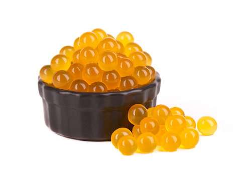 Yellow tapioca pearls for bubble tea isolated on white background. Tapioca pearls in black ceramic bowl