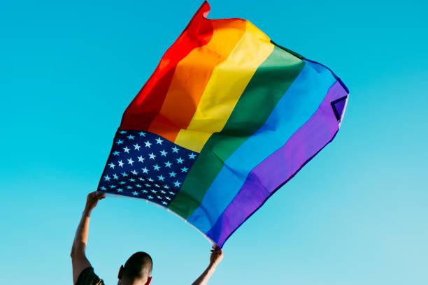 istock man waving a rainbow US flag on the sky 1326053271