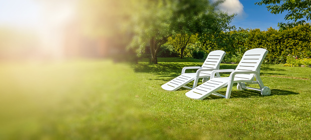 garden furniture - white loungers on green grass in backyard. copy space