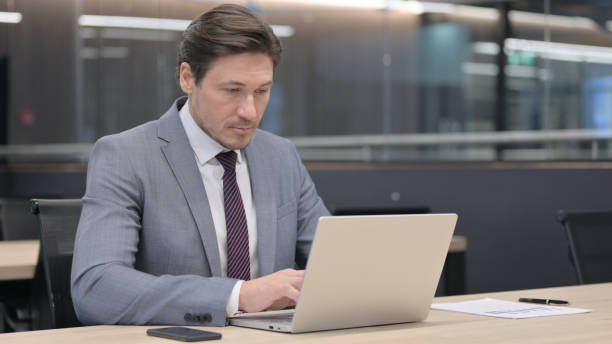 istock Middle Aged Businessman Working on Laptop in Office 1326053435
