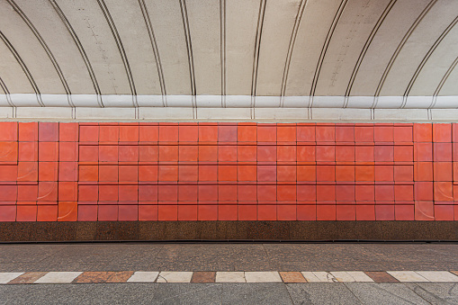 Old track wall at the metro station, lined with shabby red glazed ceramic tiles.