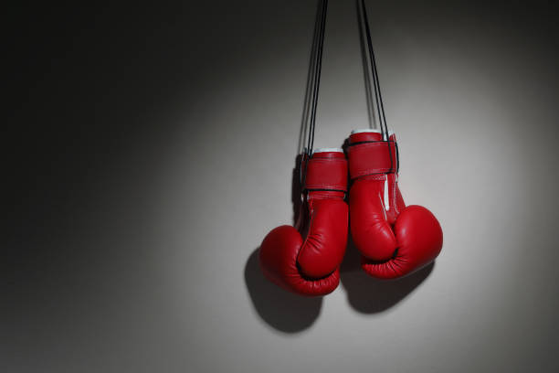 istock Pair of boxing gloves hanging on beige wall, space for text 1326059875
