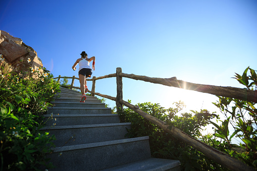Determined woman ultramarathon runner running up on mountain stairs