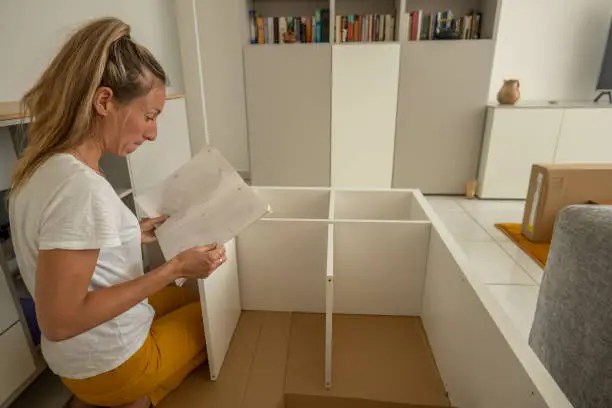 Young woman Putting Together Self Assembly Furniture In New Home