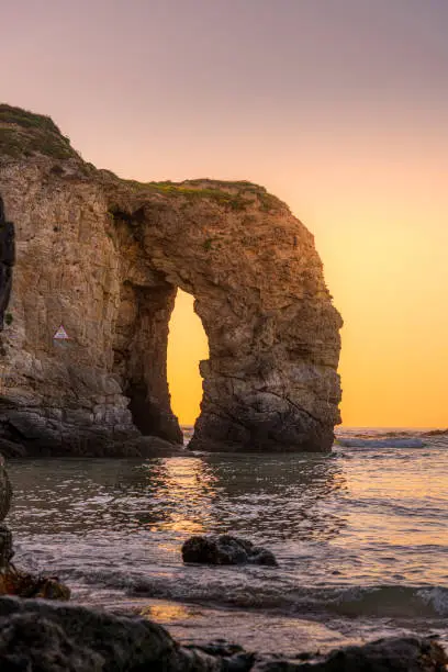 The golden glow of sunset behind the sea arch at Perranporth, Cornwall in early summer